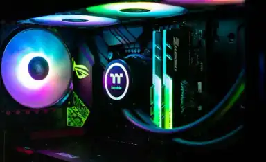 Comparativa visual de la placa base de PlayStation 5 y una tarjeta gráfica para PC sobre fondo oscuro
